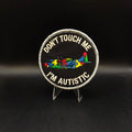 Patch with 'Don't Touch Me I'm Autistic' text and colorful symbols on a black background