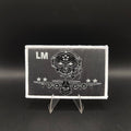 Black and white patch with skull design and 'LM' initials on a stand against a black background loadmaster aircrew kc-130j c-130 crew patch